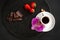 Cup of black coffee, brown sugar, strawberries, black chocolate on a round slate on a black background