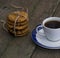 Cup of black coffee and linking of cookies on the old desktop