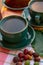 Cup with black coffee served outside with raw green, mature red and roasted coffee beans, decorated with green leaves from coffee