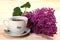 Cup of black tea and branch of lilacs on wooden background
