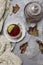 Cup with black tea and lemon and saucer, maple leaves and knitted scarf near, an gray background