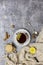 Cup with black tea and lemon and saucer, spoon, lemon, hazelnut, sticks of cinnamon and knitted scarf near, an gray background