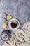 Cup with black tea and lemon and saucer, teapot, lemon, hazelnut, sticks of cinnamon and knitted scarf near, an gray background