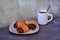 A cup of black tea and a plate with three twisted buns with poppy seeds on a gray abstract background