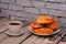 A cup of black tea with a spoon on a saucer and a plate with an assortment of homemade cakes on a wooden table against a brick