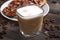 A cup of branded coffee in a scene of coffee beans and a wooden table top. Preparation of cappuccino.