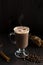 Cup of cacao. glass of hot chocolate with whipped cream, coffee beans and cinnamon sticks on a dark background.