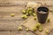 Cup of calming herbal tea with fresh wild hops. Hops cones in sack on vintage boards background