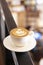 Cup of cappuccino on the background of the cafe in defocus. White ceramic cup and place for text