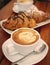 The cup of cappuccino with chocolate croissants in the background - traditional italian breakfast