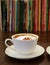 Cup of Cappuccino Coffee with Blurry Rows of Books in the Backdrop