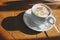 Cup of cappuccino coffee with foam and cinnamon on a wooden table. Hard morning light