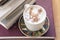 cup with cappuccino coffee and a small tower of books on a rustic wooden table