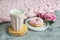 Cup with cappuccino, doughnut, pink pastel giant blanket, flowers