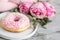 Cup with cappuccino, doughnut, pink pastel giant blanket, flowers