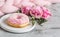 Cup with cappuccino, doughnut, pink pastel giant blanket, flowers