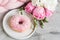 Cup with cappuccino, doughnut, pink pastel giant blanket, flowers