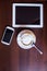 Cup of Cappuccino and mobile phone and tablet pc on wooden table