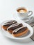 Cup of cappuccino and plate of chocolate eclairs.