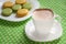 A cup of cappuccino and a plate of macaroons on the table