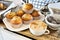 A cup of cappuccino with a plate with muffins and a white pot with truffes chocolat