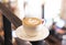 Cup of cappuccino stands on the background of the cafe in defocus. White ceramic cup and place for text