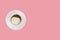 Cup of cappuccino on a white saucer on a pink background.