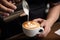 a cup of cappuchino in mans hands, barista make coffee latte art