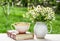 Cup of chamomile tea and chamomile in vase on table in sunny garden. Useful tea in sunny garden