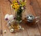 A cup of chamomile tea in a glass cup, bowl of marshmallows and a bouquet of field summer flowers on a wooden surface