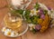 A cup of chamomile tea in a glass cup, bowl of marsmallows and a bouquet of field summer flowers on a wooden surface