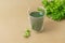 Cup of chlorophyll water on light beige background