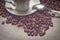 Cup of coffe alongside with coffe beans on wooden table alongside with spoon