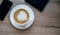 Cup of coffe with latte art standing on the wooden surface with smartphone and  tablet.