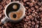 Cup of coffee americano over roasted coffee beans. Symbol yin and yang formed of foam