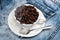 Cup with coffee beans, refined sugar and spoon on plate, denim background. Mug full of coffee beans on jeans and cloud