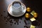 Cup of coffee with beans scattered around and chocolate bars, sweets and candy in golden wrappers on brown wooden business desk