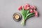 Cup of coffee with beautiful pink flowers for good morning on gray stone table top view in flat lay style. Breakfast on Mother day