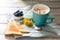 Cup with coffee with blueberries, flowers and toast