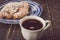 Cup of coffee with blurred croissant with almond on the blue ceramic plate