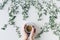 Cup of coffee in branches with green leaves on a white table. Cofee art. Flat lay, top view.