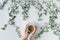 Cup of coffee in branches with green leaves on a white table. Cofee art. Flat lay, top view.