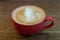 A cup of coffee or cappuccino. A beautiful red cup stands on a wooden table. Fluffy milk froth close up. Breakfast in a rural