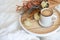 Cup of coffee cappuccino in bed on a white sheet of bedding linen with flowers. Cozy warm morning concept