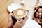 Cup of coffee cappuccino in woman hands, view from above, rose flowers in cafe