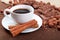 Cup of coffee with cinnamon sticks in a saucer, chocolate