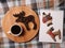 Cup of coffee, coffee beans in the shape of elk on wooden board, notebook with deer and snowman. On a plaid background