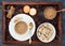 Cup of coffee, coffeepot, biscuit, cinnamon, anise, sugar, coffee beans on a wooden tray.