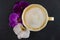 A Cup of coffee in a cozy style with a white and purple orchid. Dark background