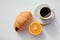 Cup of coffee, croissant and orange on white background. Top view, copy space. Morning espresso on table. Healthy breakfast.